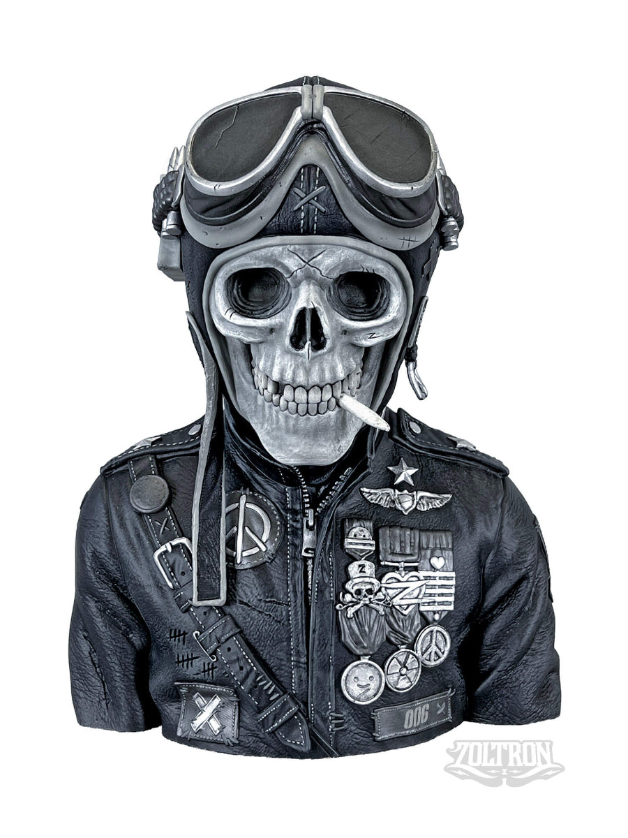 A front view close-up of award winning, extremely detailed resin and soapstone sculpture by artist Zoltron, featuring a highly detailed skull figurine wearing a cracked leather aviator helmet, a weathered black leather jacket adorned with the war medallions, pins, buttons, and detailed adornments, stitching and distress from time,  set against a plain white background. He smokes a cigarette, from a sold out edition of 100 9", six pound sculpture